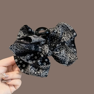 Close-up of black paisley bow hair claw clip showing fabric texture and strong inner grip