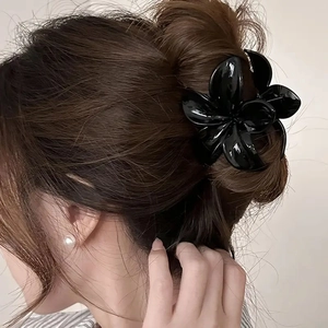 Pince à cheveux fleur noire brillante présentée en gros plan sur le modèle