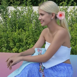 Close-up of pink gradient hibiscus flower hair claw clip worn on a blonde model
