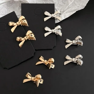Close-up of gold and silver mini bow hair clips in y2k style on display cards