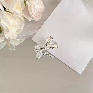 Close-up of a silver bow hair clip with a polished mirror finish on a white background
