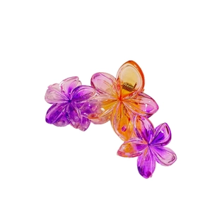 Détail de trois fleurs de frangipanier dégradées sur grande pince à cheveux à ressort