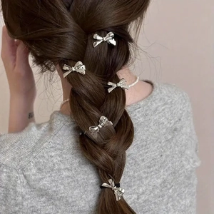 Mini silver bow hair clips in Y2K style styled on a dark braided hairstyle for women