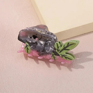 Détail macro d'une pince à cheveux koala grise avec feuille verte et dents roses