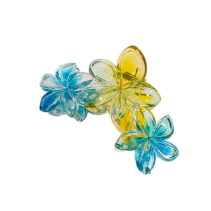 Détail d'une pince à cheveux avec trois fleurs de frangipanier dégradées en résine