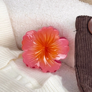 Detailed macro of a 8cm pink and orange gradient flower hair claw clip on fabric