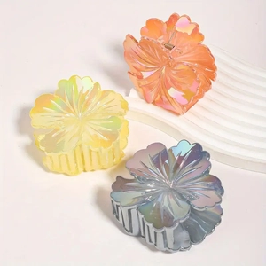 Three colorful pearlescent flower hair claws in orange pink, yellow, and blue gray