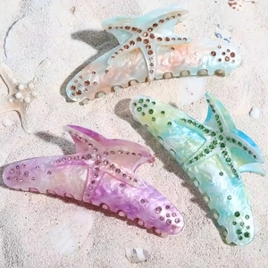 Three rhinestone starfish hair claws with marble texture on white beach sand