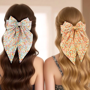 Détail de pinces à cheveux à nœud floral bleu clair et orange sur cheveux longs