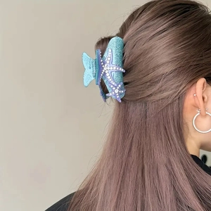 Detail of blue starfish hair claw clip with purple rhinestones on brown hair