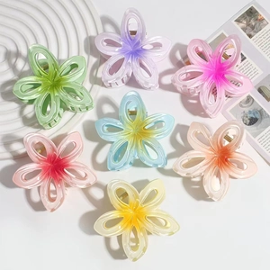 Detail of seven colorful gradient frangipani hair claw clips arranged on a tray