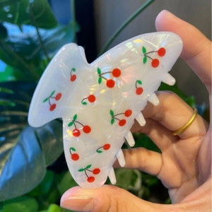 Detail of sweet cherry print hair claw clip in pearlescent white with red accents