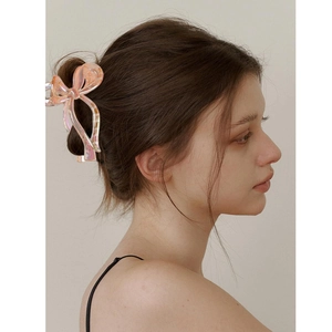 Pince à cheveux nceud rose holographique pour femme vue de côté à 45 degrés sur un modèle