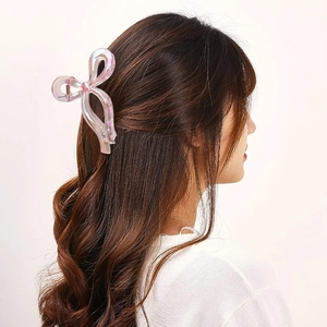 Pince à cheveux nœud irisé avec fleurs roses portée sur de longs cheveux bouclés