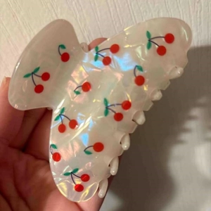 Detail of sweet cherry print hair claw clip with pearlescent finish and anti-slip teeth