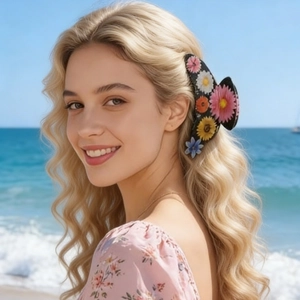 Detail view of a large floral hair claw with 3D resin flowers on wavy blonde hair