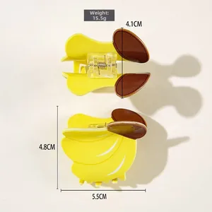 Détail de pinces à cheveux en PVC en forme de banane avec dimensions 5,5cm par 4,8cm sur fond blanc