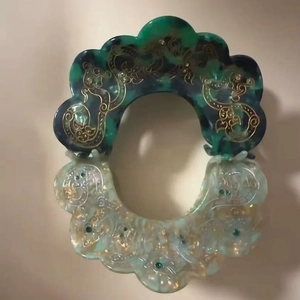 Detail of faux acetate hair claws with gold dragon motifs and marble patterns
