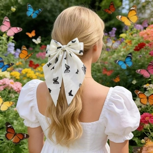 Elegante fiocco per capelli bianco con stampa a farfalla nera per donna in un giardino