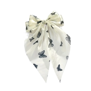 Dettaglio del fiocco per capelli color crema con farfalle nere e lunghi nastri eleganti