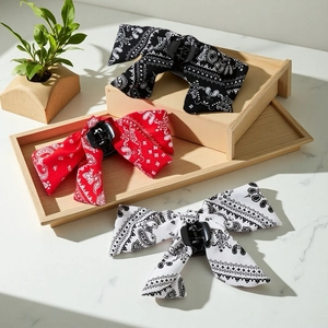 Three-piece paisley bow hair claw clip set in black red and white on a wooden tray