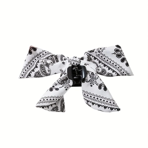 Detailed view of large white paisley bow hair claw clip with vintage floral fabric texture