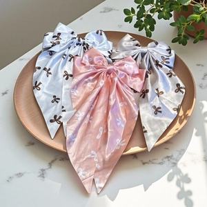 Three-piece set of sweet satin bow hair clips in white, pink, and grey with ribbon streamers