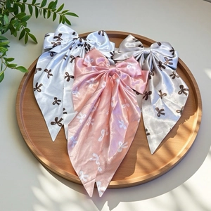 Close-up of satin bow hair clips with ribbon streamers in white, pink and grey colors