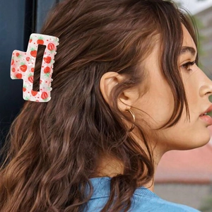 Macro detail of large rectangular strawberry print hair claw clip on brunette wavy hair