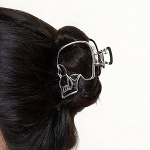 Detail of silver hollow skull hair claw clip in punk style worn on dark hair