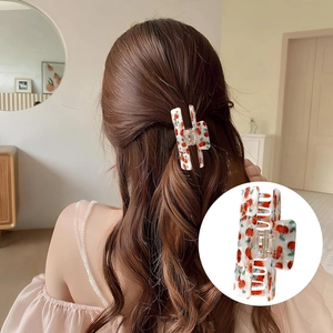 Detailed view of white hair claw clip with vibrant red cherry print on hair accessory