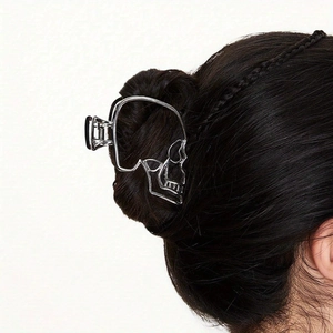 Detailed view of punk hollow skull hair claw clip in silver metal on dark hair bun