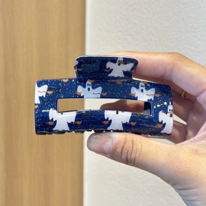 Detail of dark blue Halloween ghost hair claw clip with white spirit and broom pattern