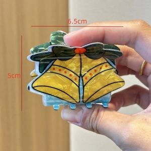 Detailed size view of yellow Christmas bell hair claw clip measuring 6.5cm by 5cm