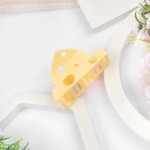 Détail d'une pince à cheveux en forme de fromage en acrylique jaune sur supports blancs