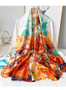 Detailed close-up of a long satin scarf with vibrant orange and blue floral print