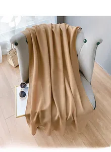 Detailed texture of khaki lightweight scarf draped elegantly over a modern grey sofa