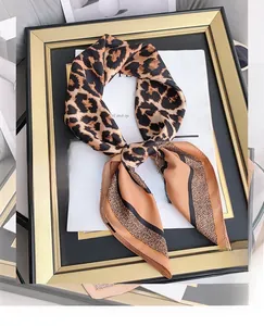 Close-up of leopard print silk scarf with orange stripes on elegant prop background