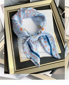 Detailed close-up of light blue floral silk square scarf with orange vintage prints