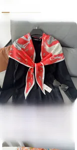 Détail macro d'un foulard en soie losange rouge avec motifs papillons et grues sur un pull