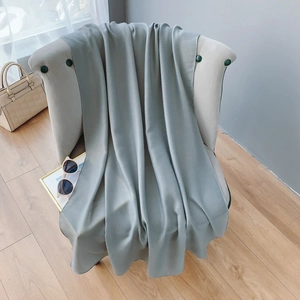 Detailed texture of sage green cotton linen scarf with silky finish draped on chair