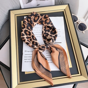 Chic leopard print silk scarf styled in a bow tie with elegant sunglasses and a gold frame