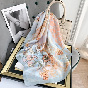 Detail of floral silk square scarf in light blue with orange flower patterns on a frame