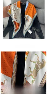 Detail of the orange horse pattern silk scarf showing premium stitching and fabric texture