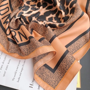 Close-up of leopard print silk scarf with letters on a book, showcasing soft texture