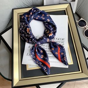 Detail of silk-like blue square scarf with floral prints and orange border on magazine