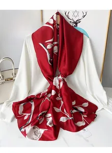Macro detail of red silk scarf with white floral print draped over a white blouse