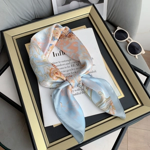Elegant light blue and orange floral satin scarf displayed over a fashion magazine