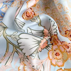 Detail of floral silk scarf showing elegant light blue fabric and orange flower patterns