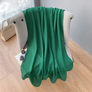 Detailed texture of an emerald green cotton linen scarf draped on a chair